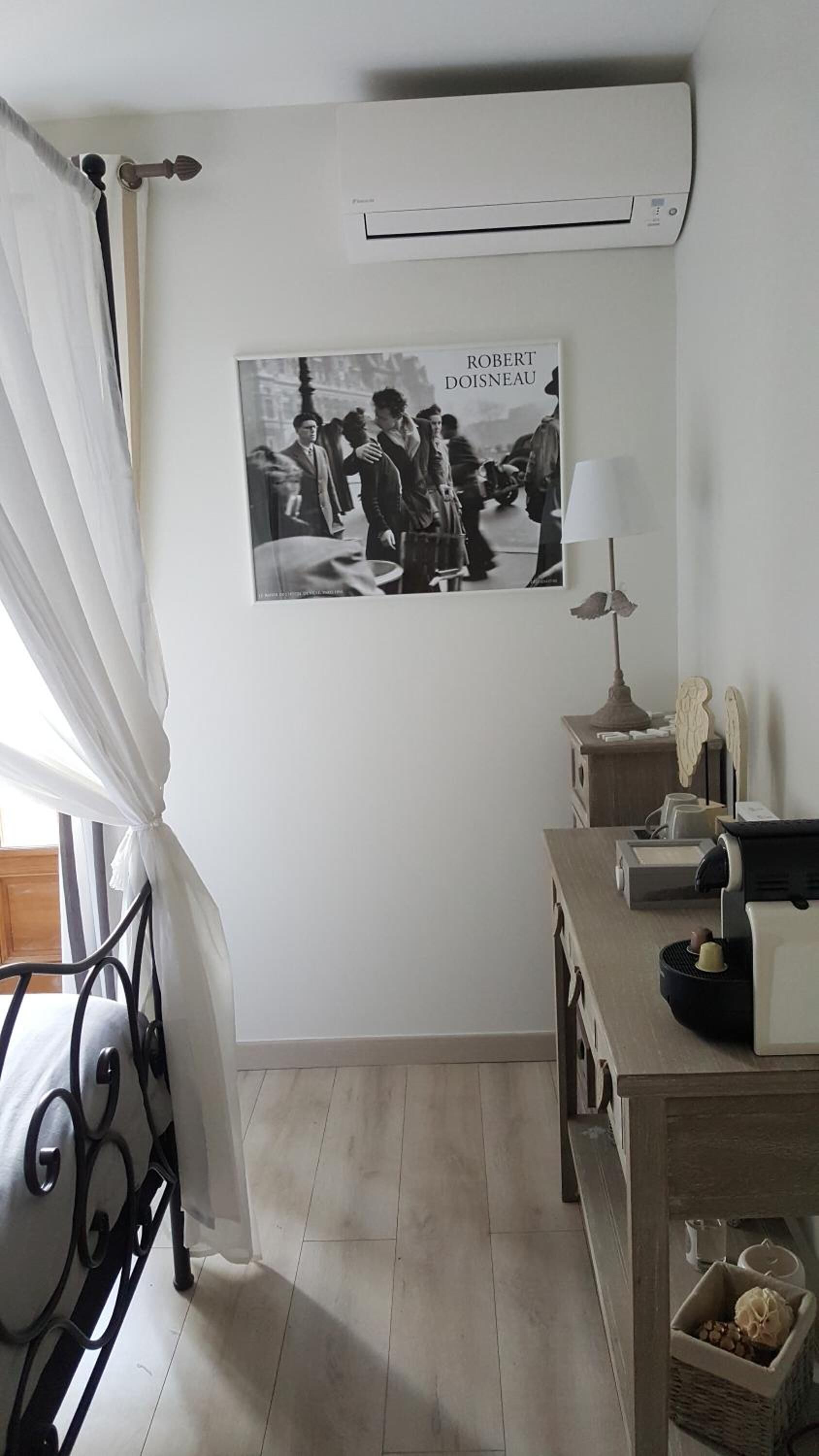 A room with a bed, a desk, a lamp, a picture frame, and an air conditioning unit.