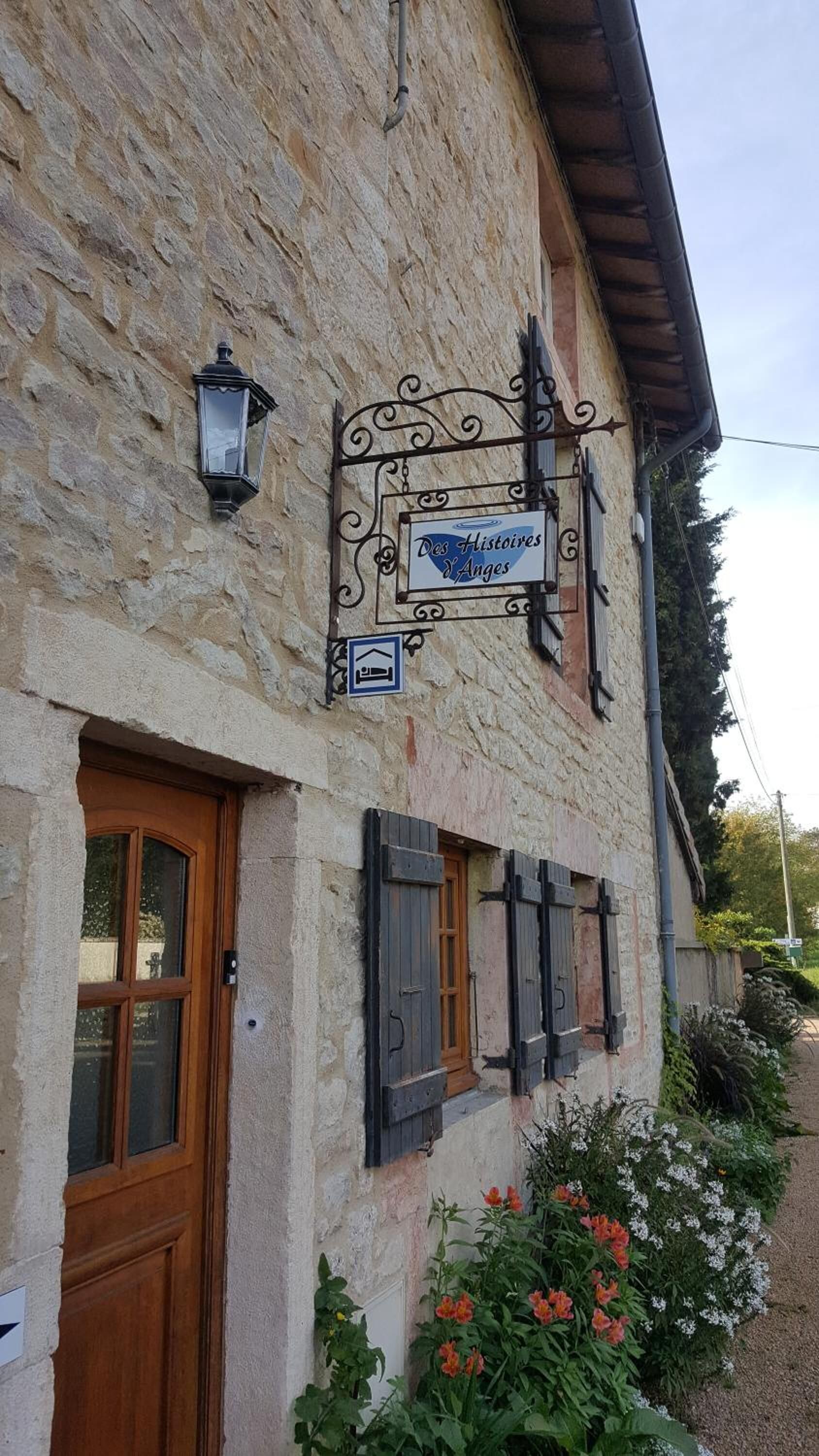 En bygning af sten med et skilt, der siger "Des Histoires Y Anges", og et ikon for en seng, hvilket indikerer et bed and breakfast.