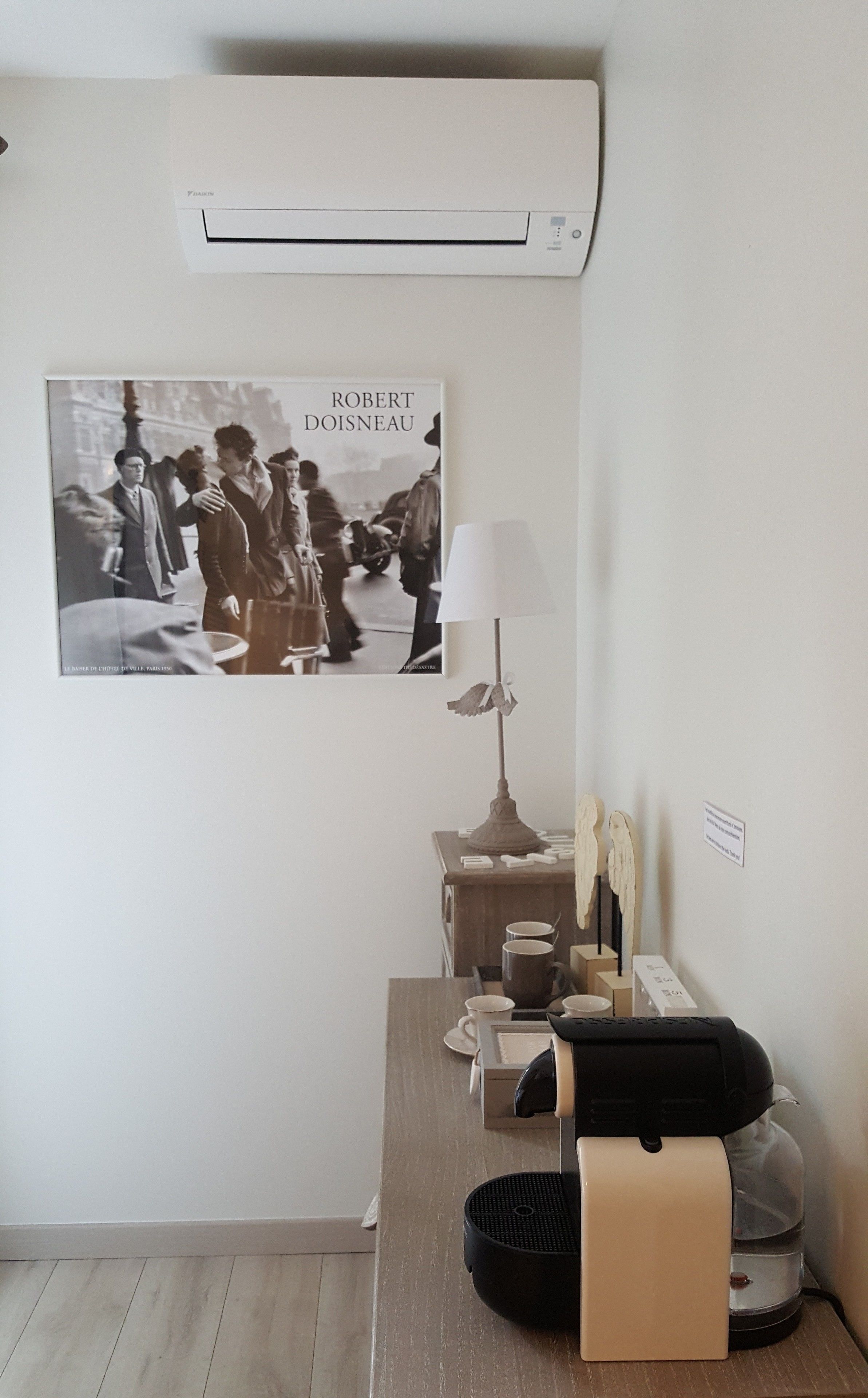A room with a bed, bedside table, lamp, and a poster on the wall.