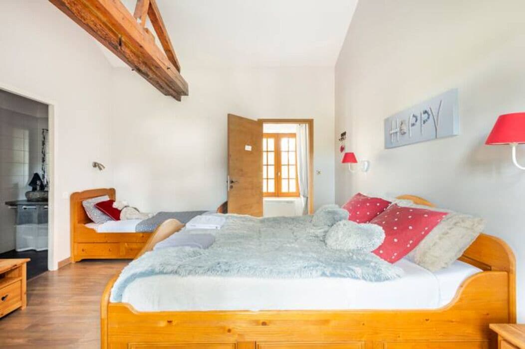 A cozy bedroom with a wooden bed, a fluffy blanket, and a red lamp.