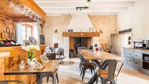 A rustic interior with a wooden bar, a fireplace, and a dining area with metal chairs.
