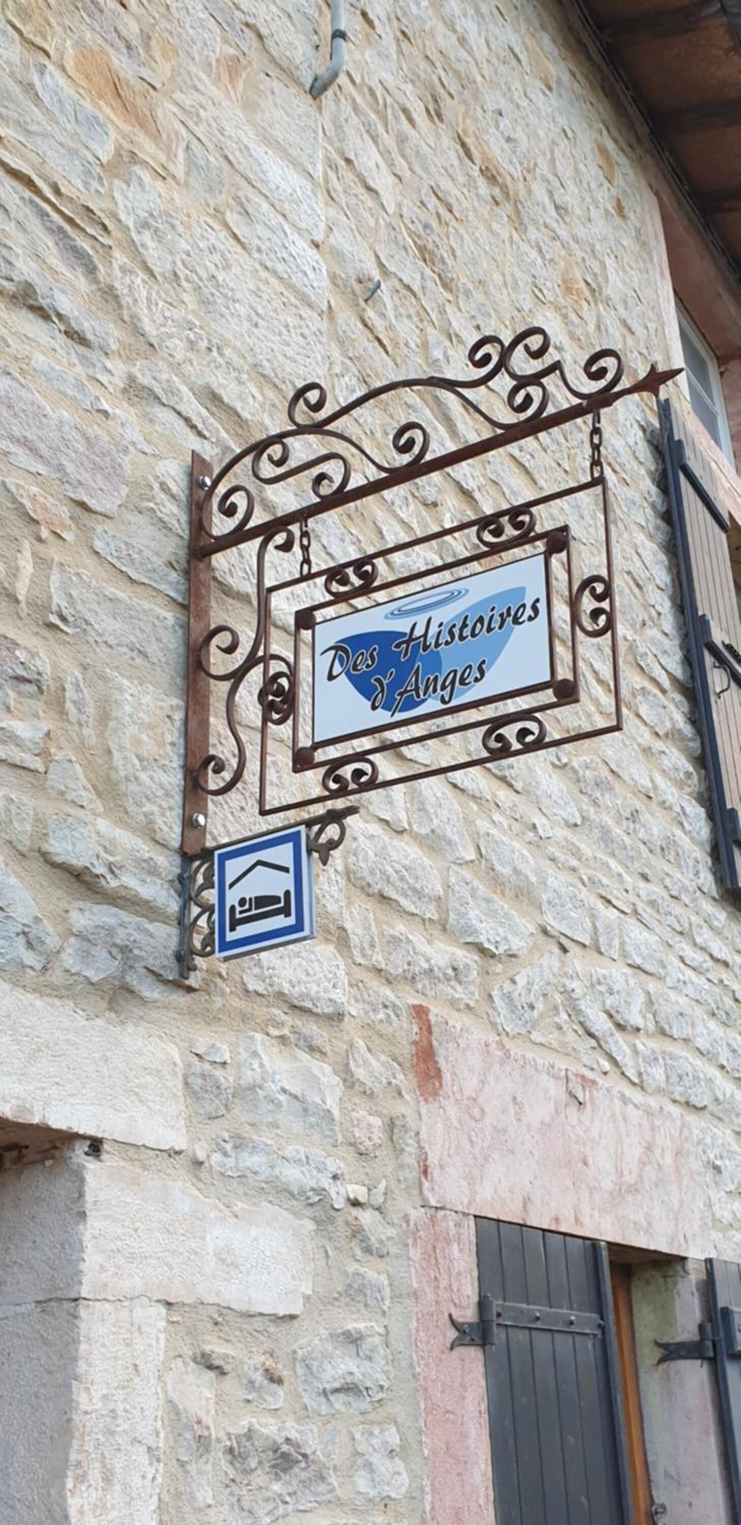 A stone building with a sign that reads "Des Histoires d'Anges" and a bed icon indicating a bed available.