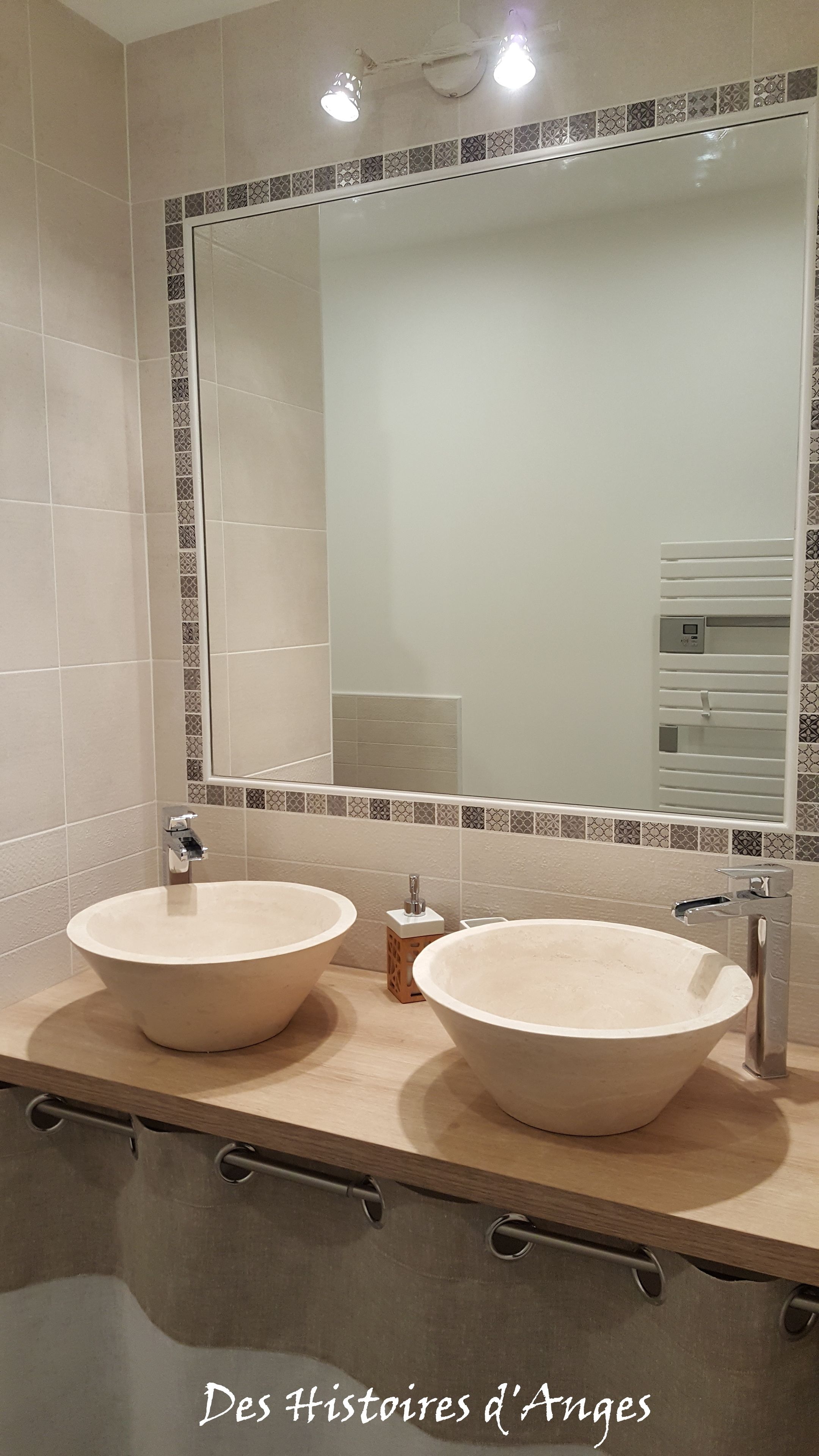 Un baño con dos lavamanos grandes y redondos, un espejo y un perchero para toallas.