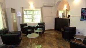 A lobby with leather chairs, a reception desk, and a tiled floor. - Nordic Hospitality Hotel (Abuja)