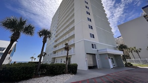 Um hotel alto e moderno, com vários andares e varandas, situado perto de uma praia.