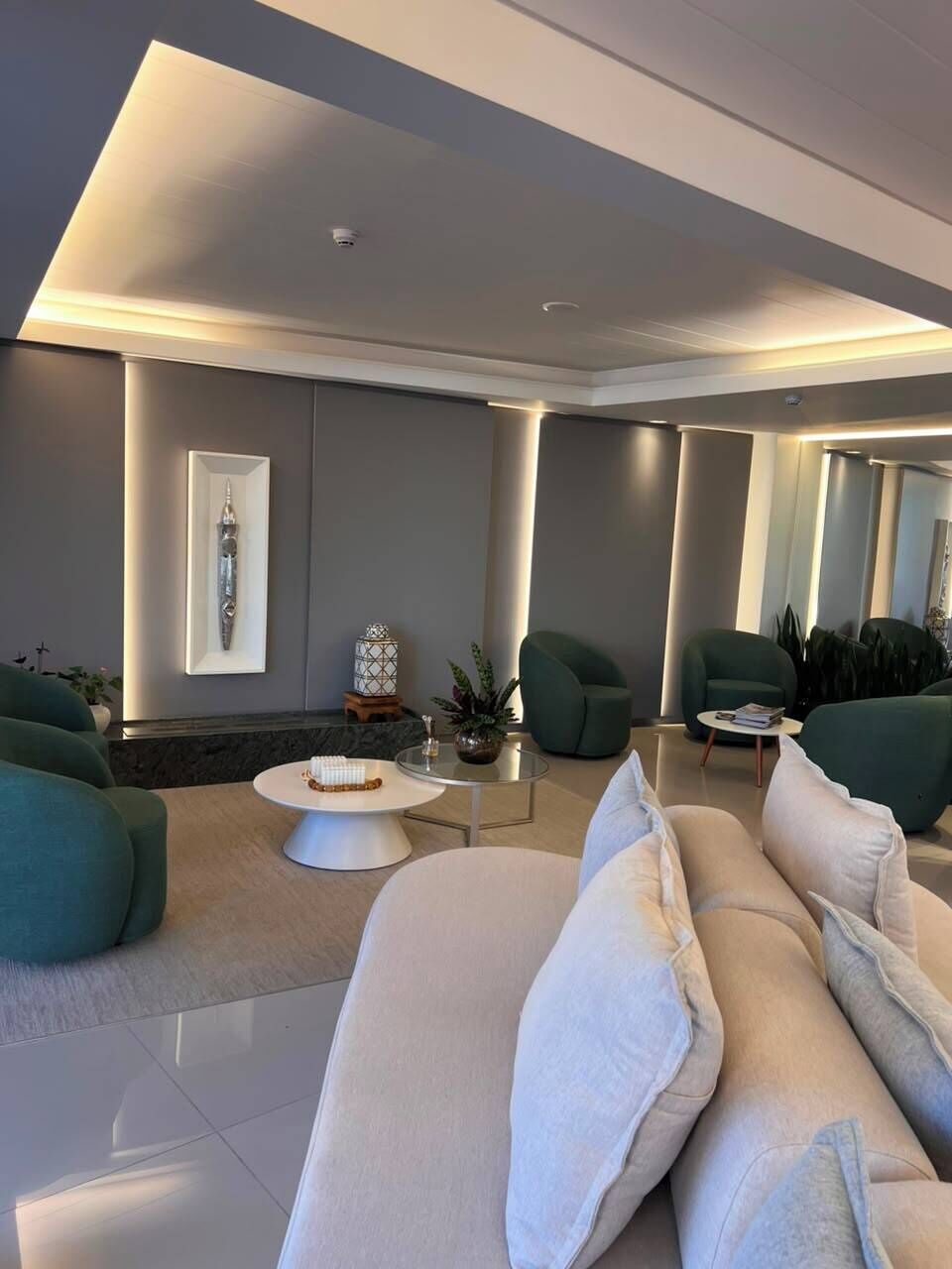 A modern living room with a sofa, armchairs, a coffee table, and a decorative item on the wall.