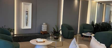A modern living room with a sofa, armchairs, a coffee table, and a decorative item on the wall.