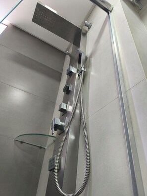 A modern shower with a handheld showerhead, a fixed showerhead, and a control panel. - Hotel San Pietro (Pato Branco)