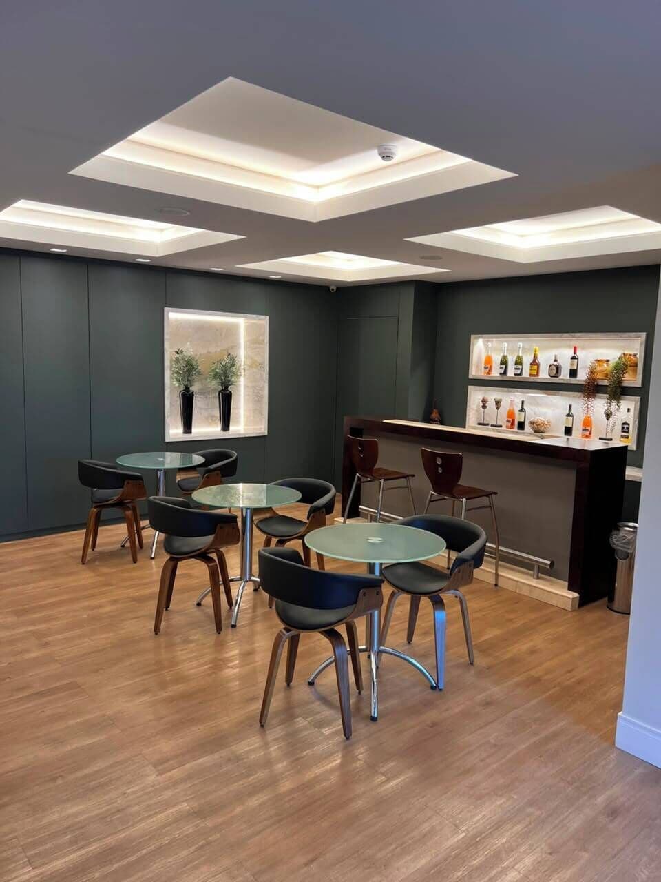 Ein modernes Interieur mit Barbereich, runden Tischen und Stühlen.