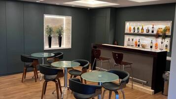 Ein modernes Interieur mit Barbereich, runden Tischen und Stühlen.