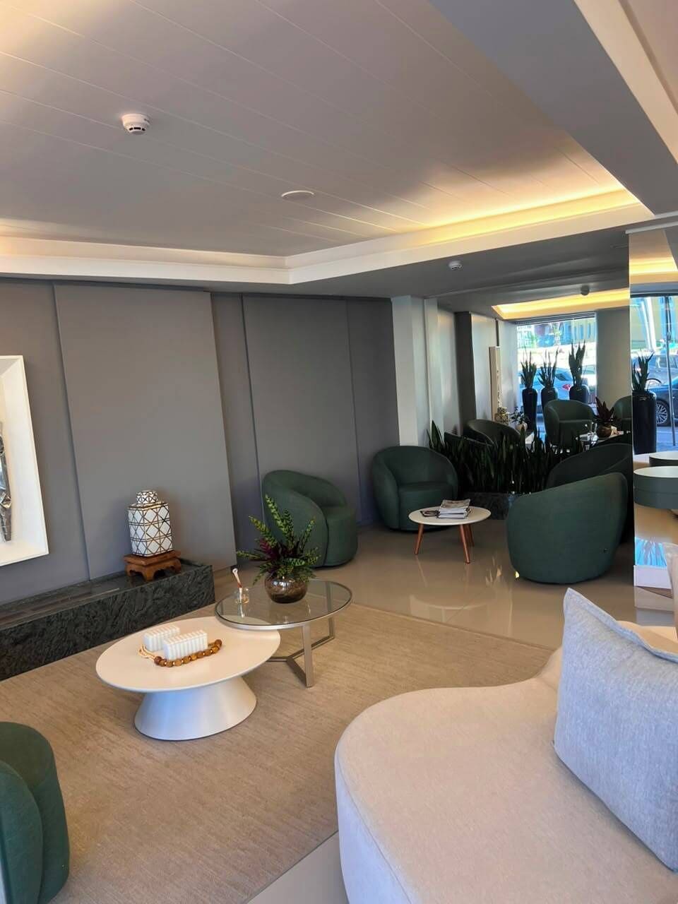 A modern lobby with seating areas, a reception desk, and a view of the outside.