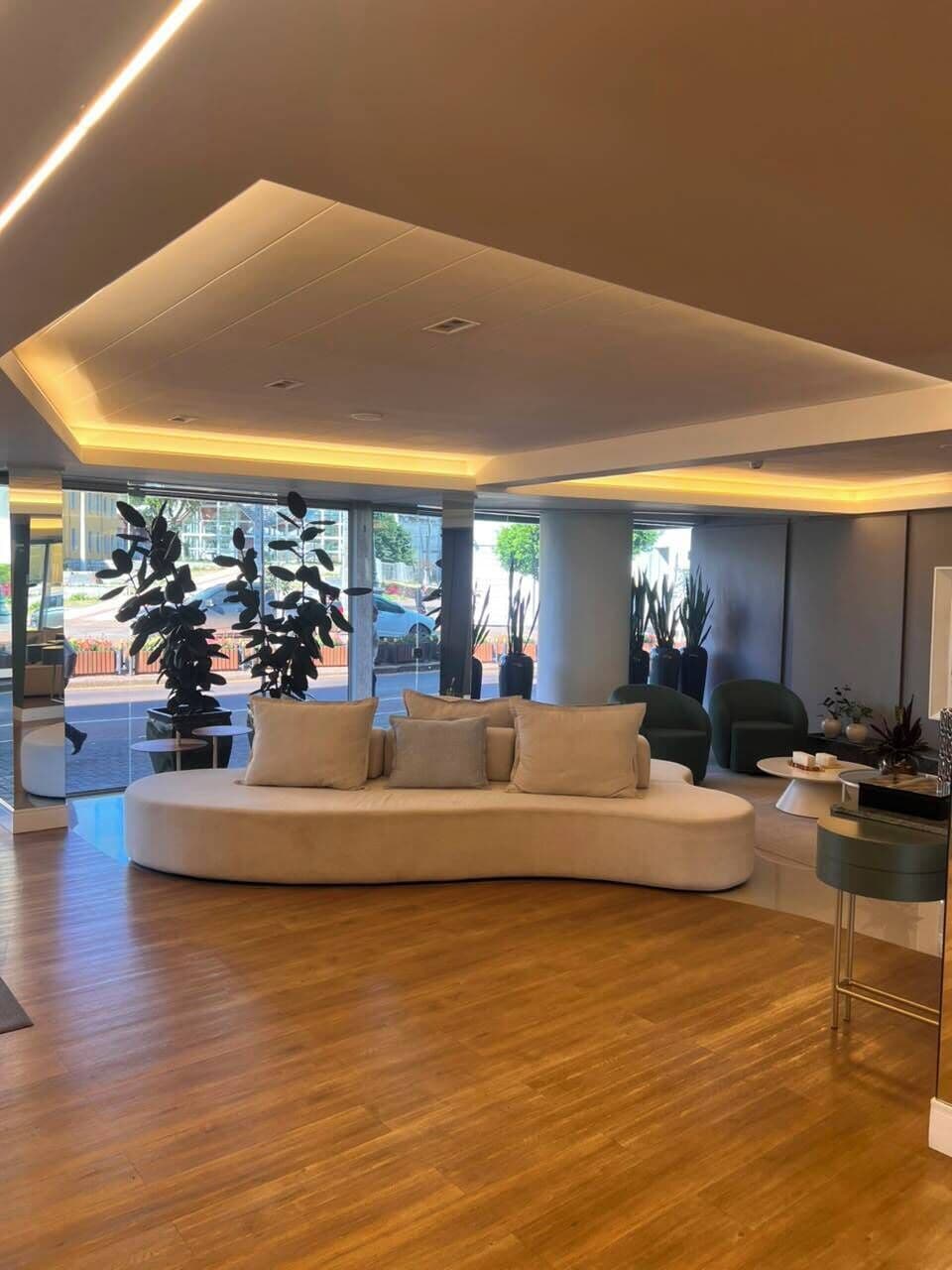 Un moderno salón con un sofá curvo, una mesa de centro y un ventanal con vistas a la calle.