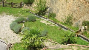 A garden with a stone pathway, a wooden fence, and a rocky hillside.