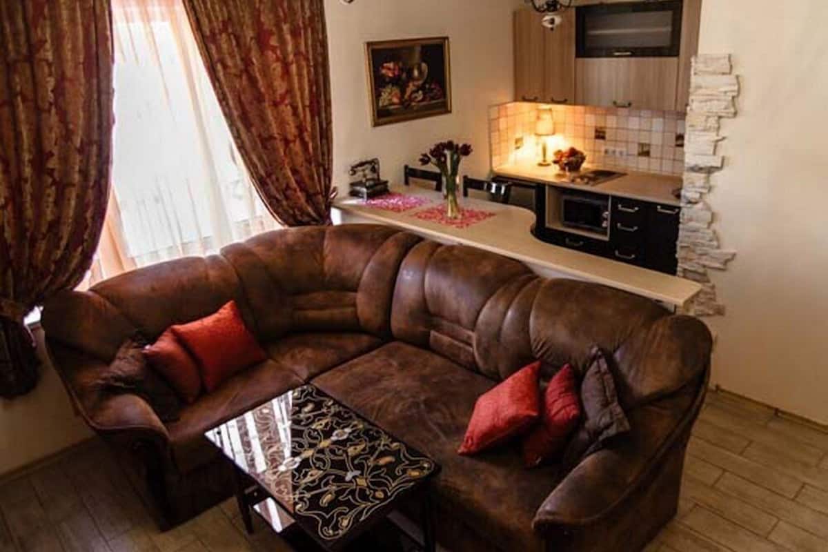 Ein Wohnzimmer mit braunem Ledersofa, einem Couchtisch und einer Küche im Hintergrund.