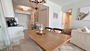 A spacious kitchen with a wooden dining table, white cabinets, and a bench.