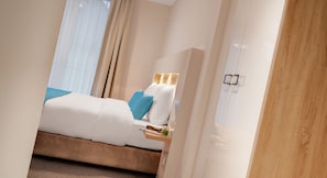 A hotel room with a bed, a bedside table, a lamp, and a window with curtains. - Seereich Hotel & Pension (Lindau)