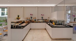 A modern kitchen with white cabinets, a black countertop, and a variety of food items and utensils. - Seereich Hotel & Pension (Lindau)