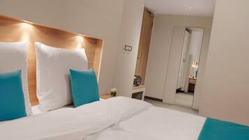 A hotel room with a large bed, a wooden headboard, and a mirror in the background.