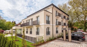 A multi-story residential building with balconies, a covered outdoor seating area, and a paved driveway. - Seereich Hotel & Pension (Lindau)
