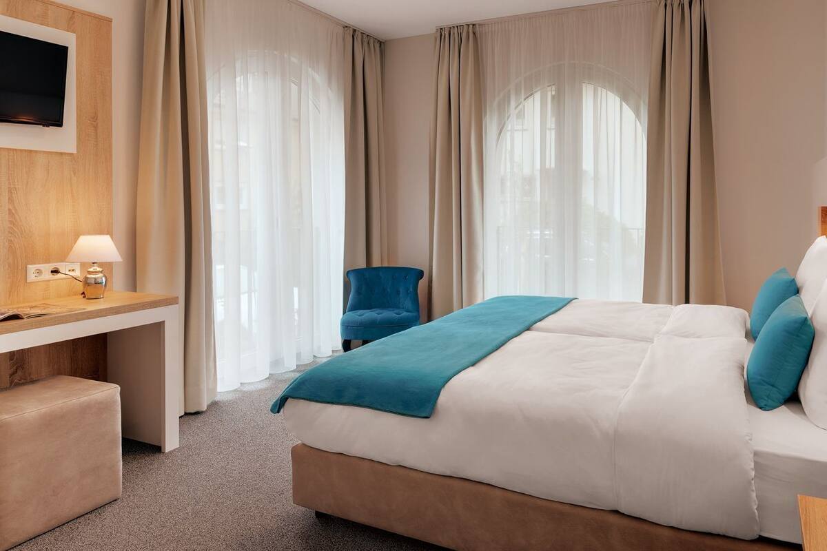 A hotel room with a bed, a desk, a chair, and a TV.