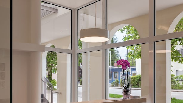 A reception desk with a glass panel, a wooden counter, and a hanging light fixture. - Seereich Hotel & Pension (Lindau)
