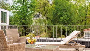 A balcony with wicker furniture, a glass table, and a fruit bowl. - Seereich Hotel & Pension (Lindau)