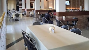 Un restaurante moderno con una barra central, varias mesas para comer y sillas.