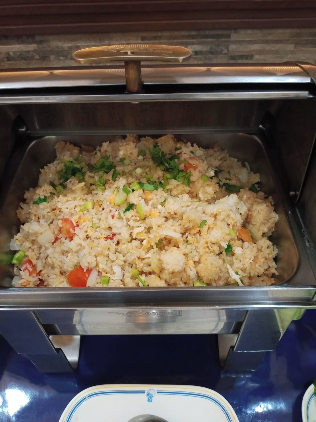 A buffet with a variety of dishes, including fried rice with vegetables and possibly meat.