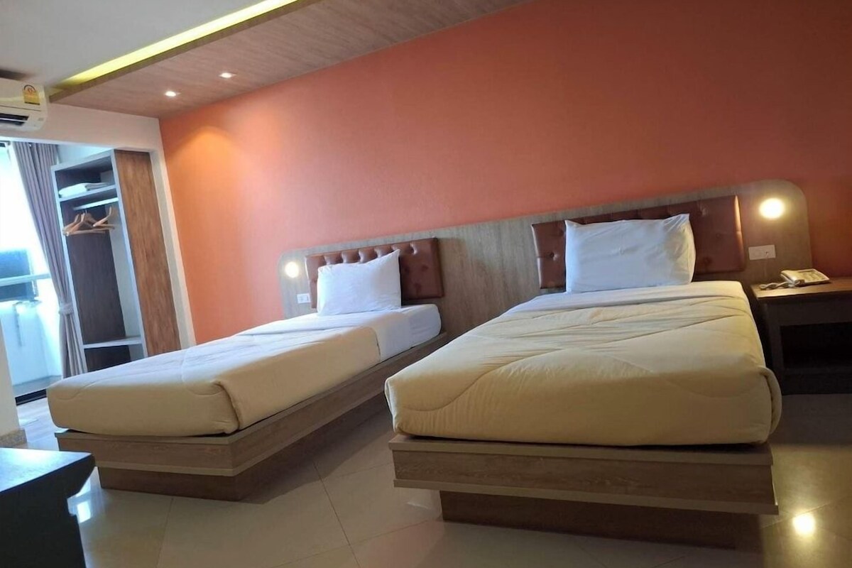 Une chambre d’hôtel avec deux lits, une armoire et une table de chevet.