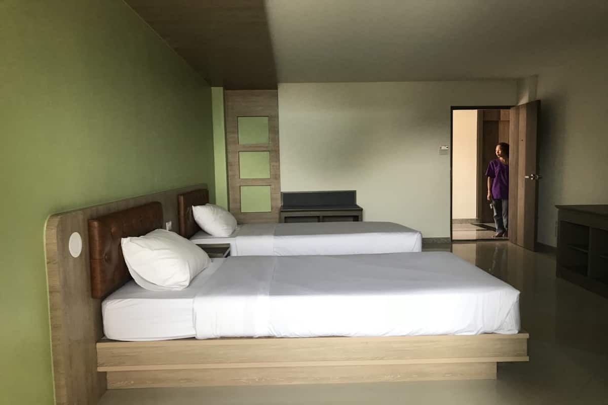 A bedroom with two beds, a wooden headboard, a nightstand, and a TV stand.