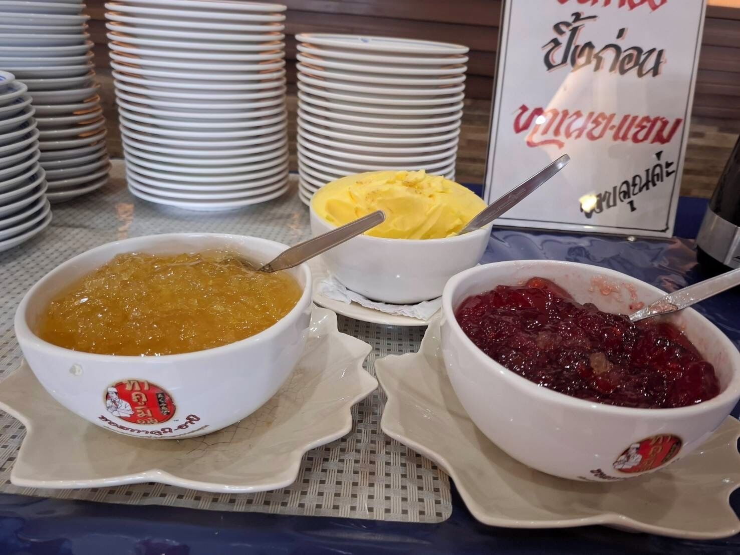 Une table de buffet avec des plats remplis de nourriture, notamment un dessert jaune et une compote de fruits rouges.