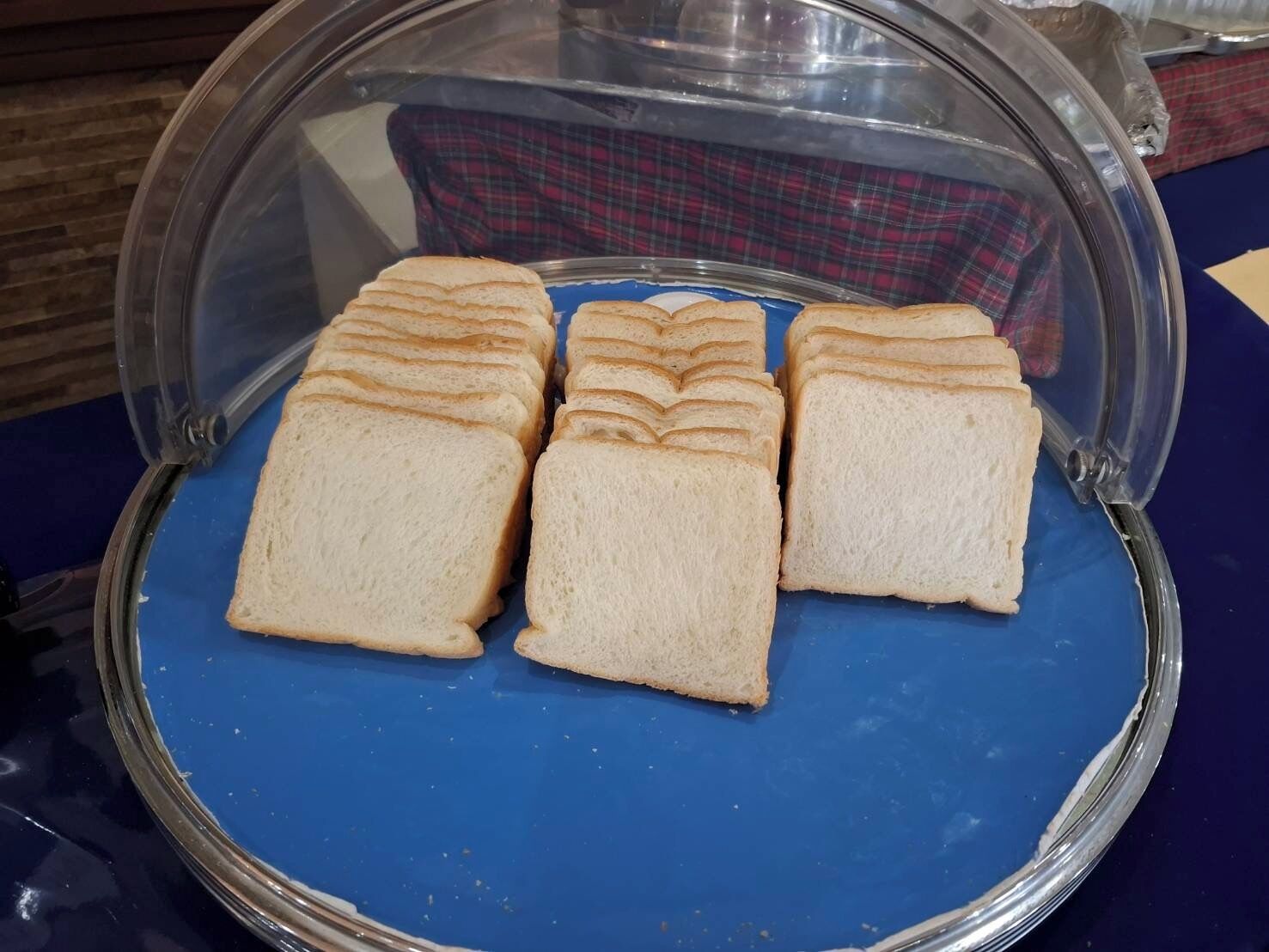 Una exhibición de alimentos con rebanadas de pan bajo una campana de vidrio.