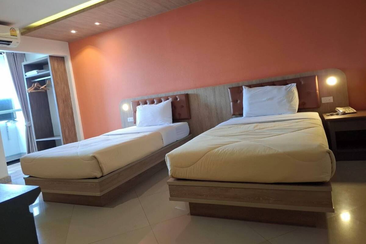 A hotel room with two beds, a wardrobe, and a desk.