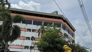 Un edificio con una estructura de varios pisos, una fuente con una estatua dorada y un cielo despejado.