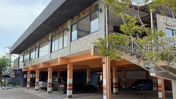 A multi-story building with a covered parking area, large windows, and a stone facade.