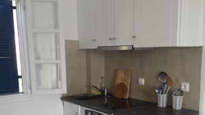 Une cuisine compacte avec des meubles blancs, un four encastré et un évier.