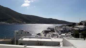 Une ville côtière avec des bâtiments qui bordent le front de mer, un ciel dégagé et une chaîne de montagnes en arrière-plan.
