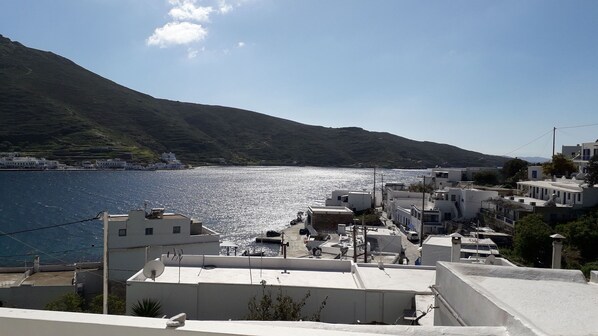 A coastal town with buildings along the waterfront, a clear sky, and a mountainous backdrop.
