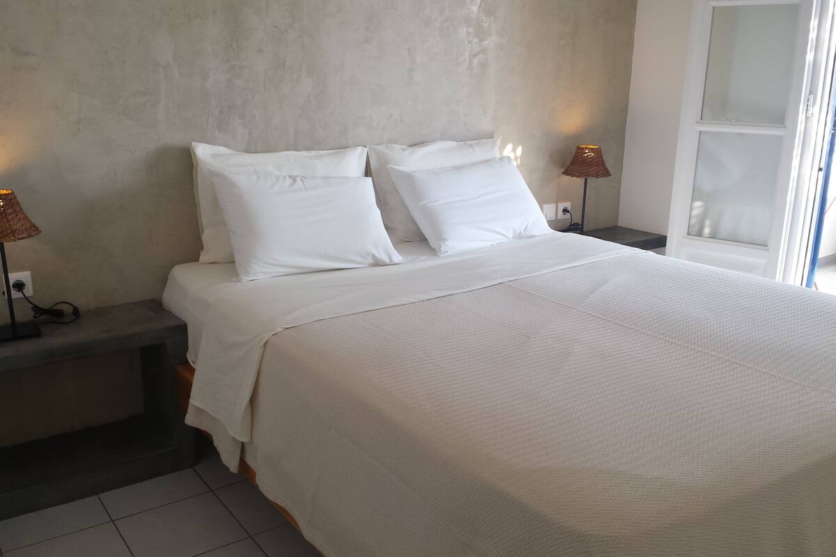 A bedroom with a bed, two bedside lamps, a nightstand, and a window.