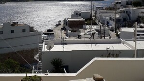 Une ville côtière aux bâtiments blancs, sous un ciel d’un bleu limpide, offrant une vue sur la mer.