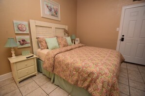 A bedroom with a bed, nightstand, lamp, and a door.