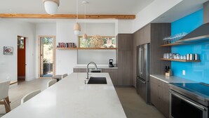 Een moderne keuken met een centraal eiland, ingebouwde apparatuur en een blauwe accentmuur.