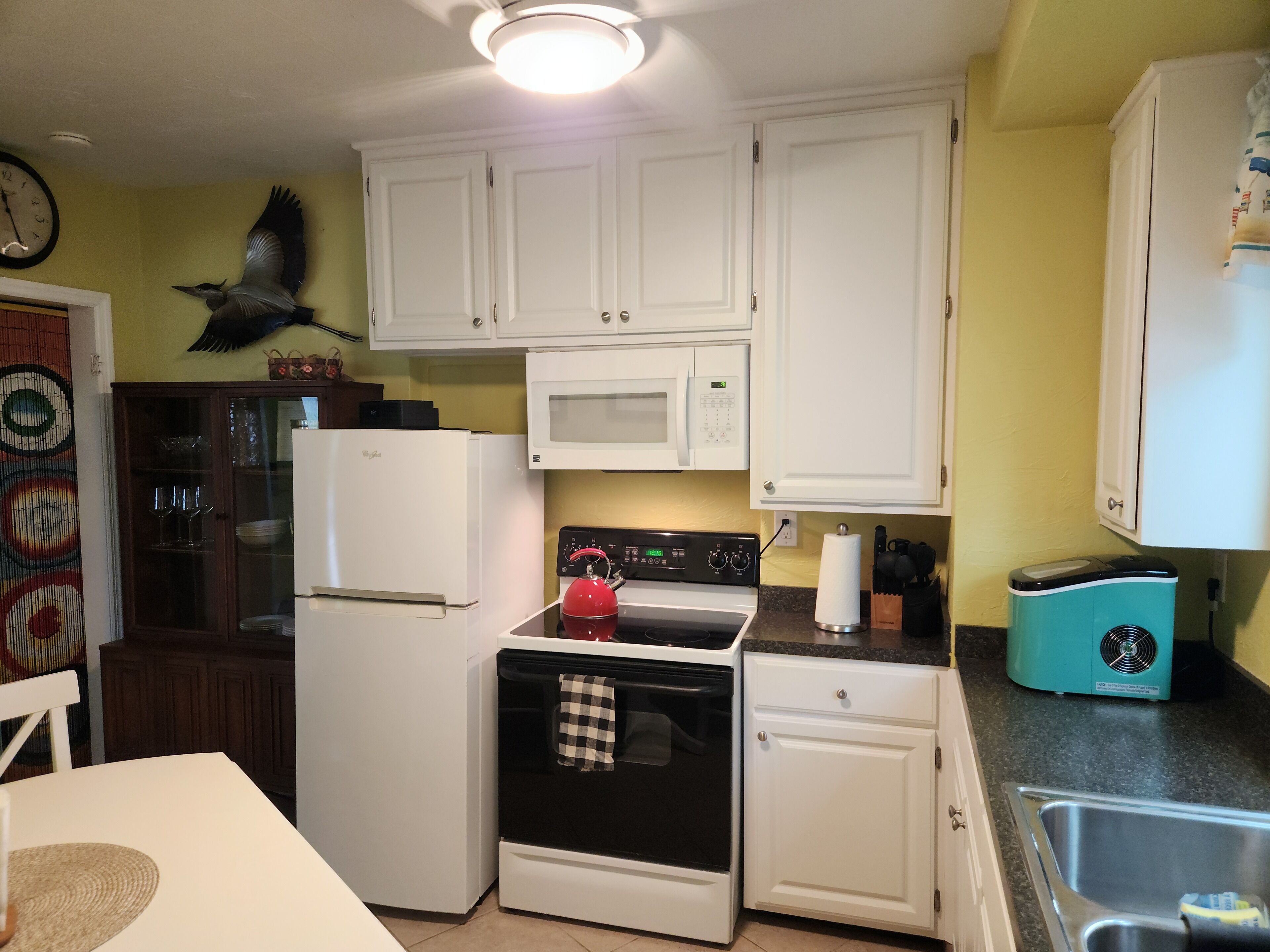 A compact kitchen with white cabinets, a microwave, a stove, and a sink.