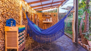 A hammock in a covered outdoor area with a stone wall and wooden logs. - Casa Agrreste Bed & Breakfast (Sopó)