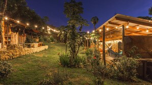 A well-lit outdoor area with a stone wall, wooden pergola, and string lights. - Casa Agrreste Bed & Breakfast (Sopó)