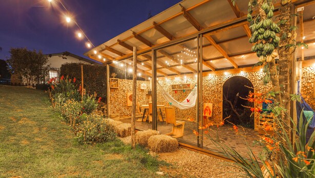An outdoor patio with a glass enclosure, stone walls, and a hammock. - Casa Agrreste Bed & Breakfast (Sopó)