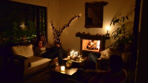 A dimly lit room with a fireplace, a sofa, and a table with candles. - Casa Agrreste Bed & Breakfast (Sopó)