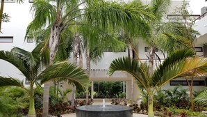 A courtyard with a central water feature surrounded by palm trees and various plants. - TAO Modern Retreat (Akumal)
