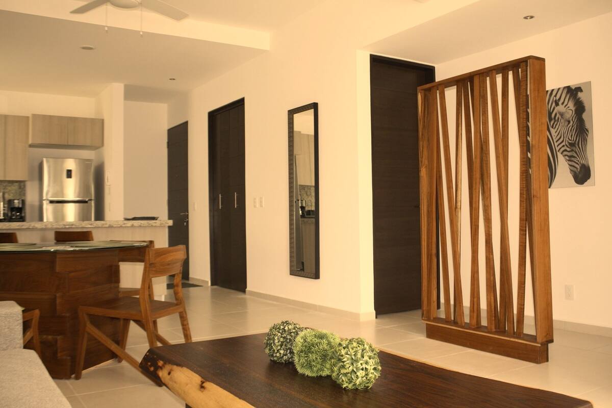 A modern kitchen with a built-in refrigerator, wooden chairs, and a dining table.