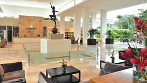 A spacious lobby with a reception desk, seating area, and a sculpture. - TAO Modern Retreat (Akumal)